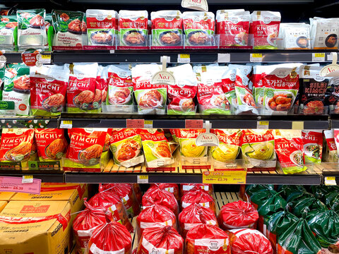 Different brands of kimchi on shelves on an Asian supermarket.