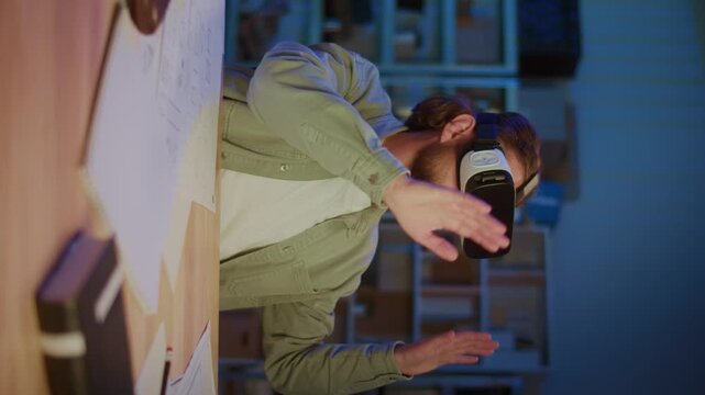 Vertical Video Bearded Man Wearing Virtual Reality Headset While Sitting At Desk With Laptop And Papers. Concept of Digital Innovation