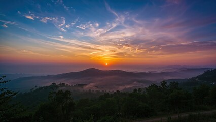 Fototapeta premium Sunrise over mountain landscape with misty forest, vibrant sky with clouds, and scenic view of hills at dawn.