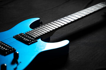 Fototapeta premium Blue electric guitar on dark stage background, symbol of rock music and creative inspiration, close-up detail with dramatic lighting