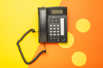 Black Landline Telephone on Vibrant Orange and Yellow Geometric Background