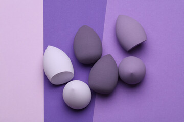 Makeup eggs shape blenders on purple background. Beauty concept. Top view