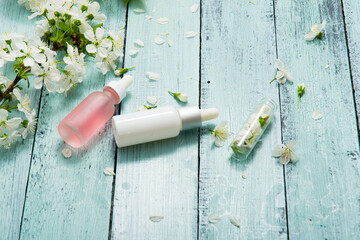 perfume droppers and cherry flowers on old blue wood table