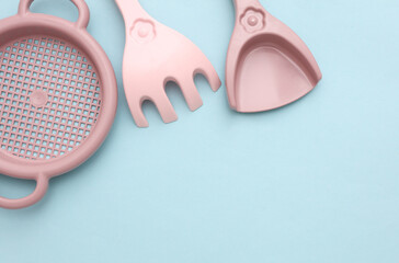 Children's sand sieve, rake and shovel on a blue background. Top view