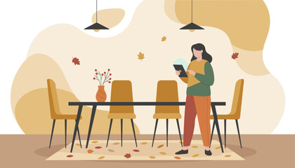 Woman browsing on a tablet in a modern dining room featuring autumn decor and warm colors
