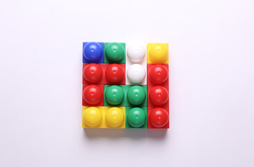 Toy plastic bricks assembled into a puzzle on a white background