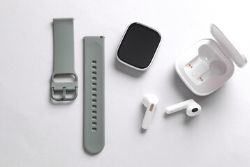 Modern gadgets. Smart bracelet and wireless earphones on a gray background