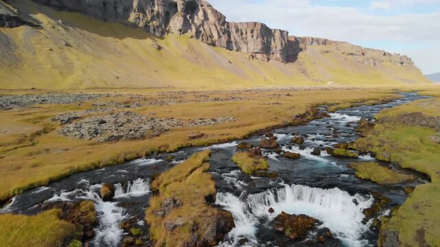 Aerial of stream at the foot of cliffs