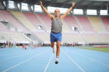 Fototapeta premium Full length portrait of a senior man running at a sports arena