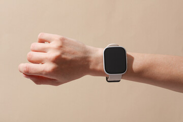 Female hand with modern smart watch on wrist, beige background