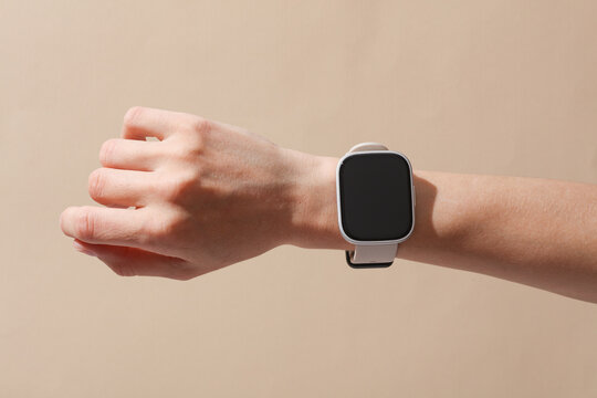 Female hand with modern smart watch on wrist, beige background