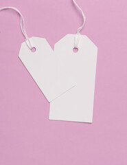 Blank white tags with ropes on pink background. Mock up, Template for design. Copy space. Sale, shopping concept
