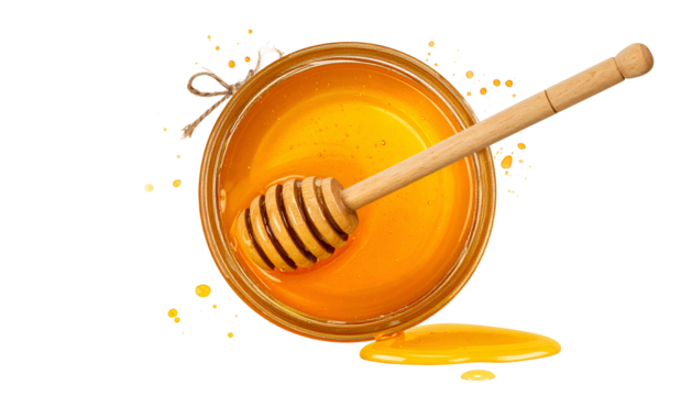 Overhead view jar of golden, thick liquid with wooden dipper, plus small puddle