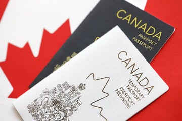 Canadian temporary and permanent passports lies on flag close up