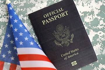 United States official passport book with US flag on camouflage uniform close up. Travel document on camo fabric photo