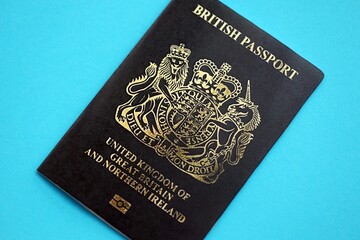 British passport book on light blue paper background close up. Travel document on blue surface
