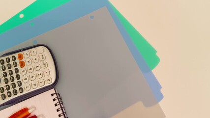 Student's workspace showing calculator and colorful folders for organizing schoolwork, perfect for back to school promotions or educational content creation with study tools - Powered by Adobe