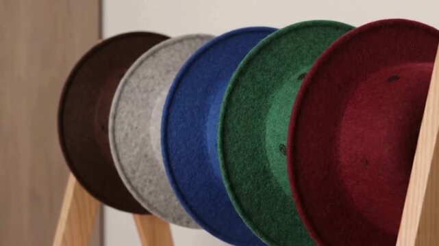 Row of colorful felt hats displayed on wooden stands, offering a vibrant collection of fashion accessories.