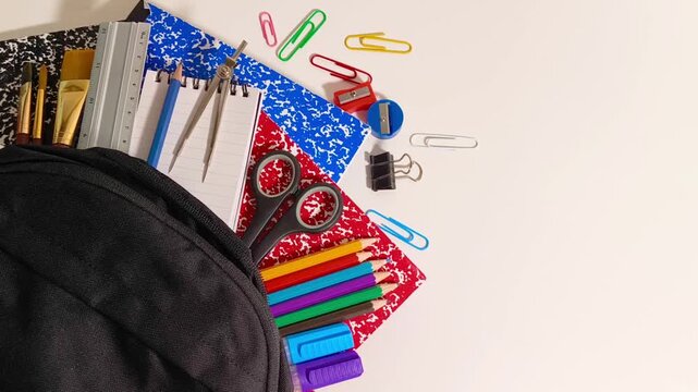 Back to school supplies with scissor, books, markers, colored pencil crayons, gel pens, ruler, sharpener, compass, calculator, notepad, paper clips in a backpack education, student, children, learning