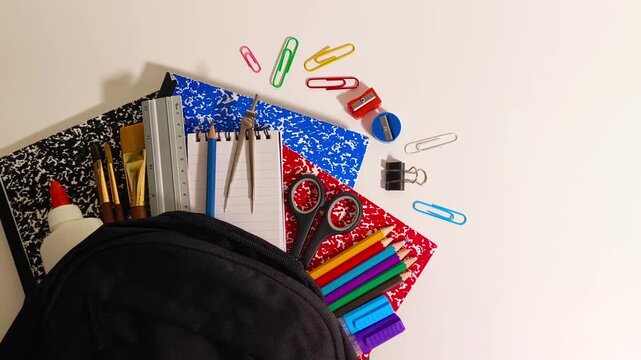Back to school supplies with scissor, books, markers, colored pencil crayons, gel pens, ruler, sharpener, compass, calculator, notepad, paper clips in a backpack education, student, children, learning