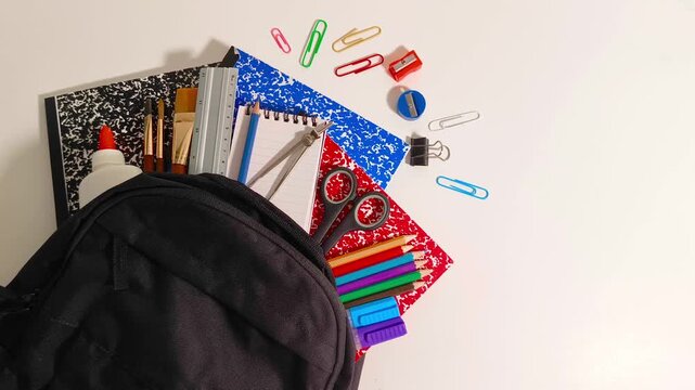 Back to school supplies with scissor, books, markers, colored pencil crayons, gel pens, ruler, sharpener, compass, calculator, notepad, paper clips in a backpack education, student, children, learning