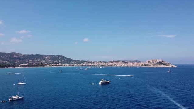 Aerial view of Calvi coastline, Corsica on a sunny summer day. Mediterranean Sea and boats near the citadel.