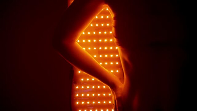 Woman enjoys skincare with red light therapy panel at home setting