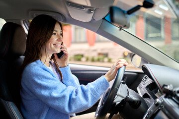 Candid photo of young happy woman customer driver sitting inside car driving a car talking on the...