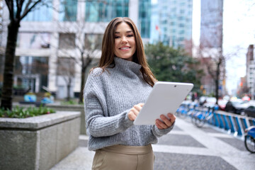 Young happy busy business woman professional or female student standing on big city street using...