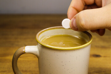 Effervescent tablet about to drop into coffee