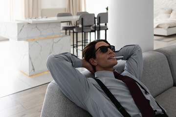 Fototapeta premium A successful and confident young yuppie smokes in his perfect apartment while sitting on the couch