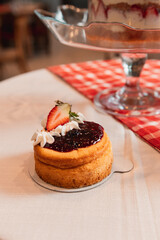 Jam tart with a strawberry on top, served at a restaurant table.