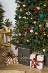 Beautifully decorated Christmas tree with colorful ornaments and gift boxes wrapped in festive paper under it.