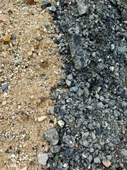 Junction of yellow sand and black gravel, contrasting natural texture background with copy space