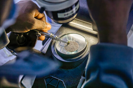 african worker at a diamond polishing factory, gemological microscopes in lab diamond factory to precisely inspect diamonds for quality control, grading, and polishing