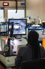 Woman with dreadlocks, braids is using a machine that displays a magnified view of a diamond on a screen