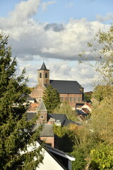 Fototapeta premium L'église Saint-Rémy dominant les toits des maisons traditionnelles sous un ciel nuageux à Écaussinnes-Lalaing (Soignies)