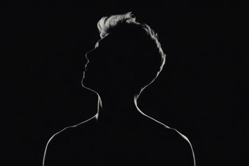 Silhouette of a man looking up dramatic lighting on a dark background for concepts of hope and aspiration