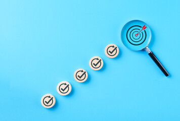 Business target and goal achievement steps concept. Wooden blocks check marks and magnifying glass on target symbolizing success, progress, growth, task completion, performance optimization strategy,