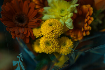 close up of a bright yellow and pink gerbera daisy bouquet wrapped in kraft paper concept of floristry, gift giving, celebration planning