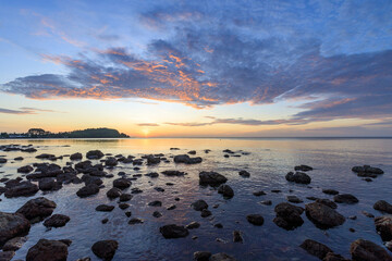 The ocean is calm and the sky is a beautiful mix of orange and blue