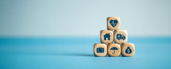 Wooden blocks with insurance icons stacked in a pyramid representing protection and security for financial planning and risk management concepts