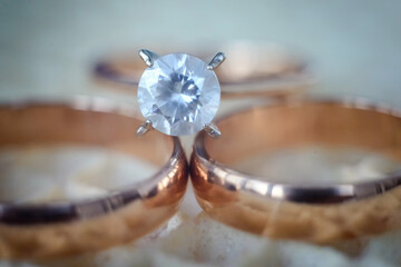 Engagement ring with diamond among golden bands. Shiny engagement ring with diamond placed between two golden wedding bands close-up
