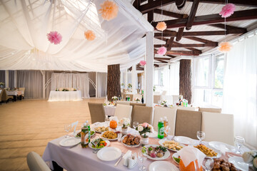 Wedding reception hall with decorated tables. Bright wedding reception hall with decorated tables, white drapery and floral arrangements