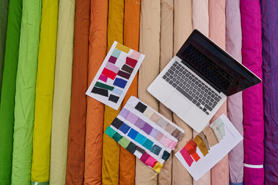 Fabric rolls and color swatches with laptop, textile industry concept, designer workspace, colorful background, fashion design process, studio shot, creative inspiration. - Powered by Adobe