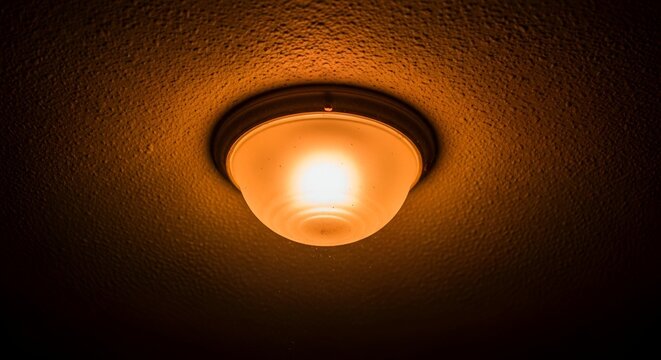 Illuminated ceiling light fixture glows in a dimly lit, textured, and warm-toned interior