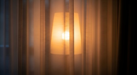 Illuminated lampshade casting warm glow behind semi-opaque vertical fabric drapery