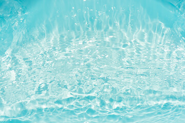 Blue water with ripples on the surface. Defocus blurred transparent blue colored clear calm water surface texture with splashes and bubbles. Water waves with shining pattern texture background.