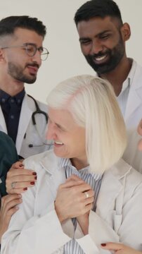 Vertical video. Diverse healthcare team applauding and celebrating a respected senior female physician&rsquo;s achievement with pride and camaraderie