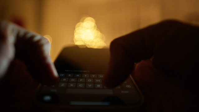 Silhouette Hands Write Merry Christmas Message on Phone in Christmas Room